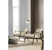 Vardagsrum med två fåtöljer, golvlampa och gardiner framför ett fönster