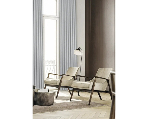 Vardagsrum med två fåtöljer, golvlampa och gardiner framför ett fönster