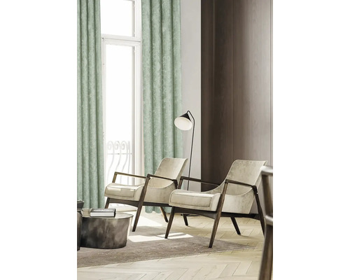 Vardagsrum med gardin, två fåtöljer, golvlampa och soffbord