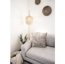 Ljus rumsscen med soffa, kudde med geometriskt mönster och golvlampa