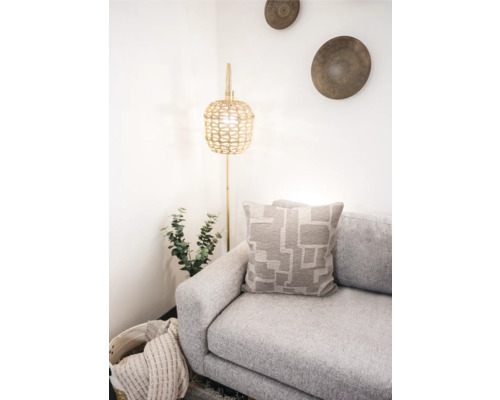 Ljus rumsscen med soffa, kudde med geometriskt mönster och golvlampa