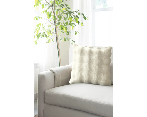 Dekorativ kudde på en soffa bredvid en krukväxt.