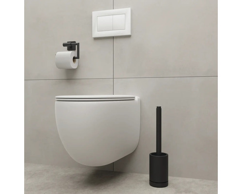 Vägghängd toalett med toalettpappershållare och toalettborste i ett badrum.