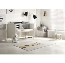 Ljust barnrum med spjälsäng, golvlampa, barnstol och matta med djurmotiv