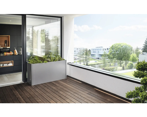 Balkongscen med en metallplanteringslåda, planterad med örter och växter, på ett trägolv