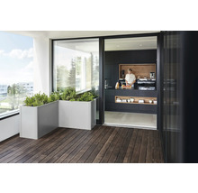 Modernt designad terrass med trägolv, planteringslådor och öppen passage till köket