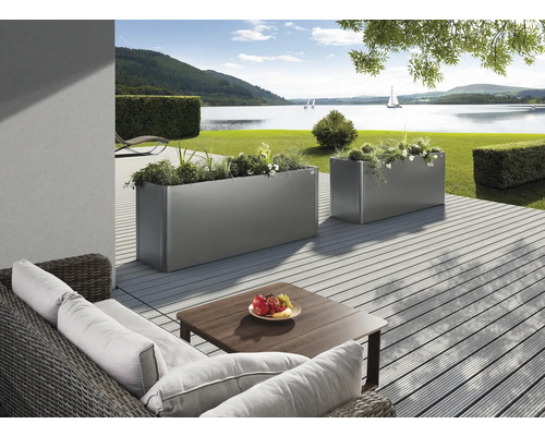 Två planterade, rektangulära metallplanteringslådor på en terrass med sjöutsikt.