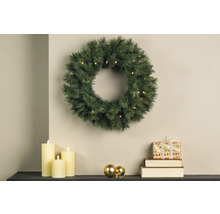 Julscen med upplyst grankrans, ljus och present