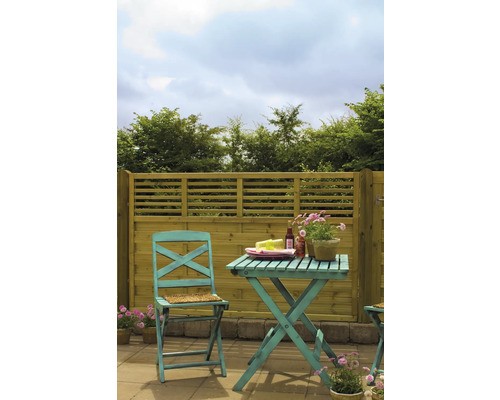 Trädgårdsscen med trästaket, bord och stol