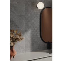 Badrum med grå väggplattor i stenlook, spegel och lampa