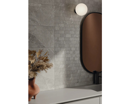 Badrum med grå väggplattor i stenlook, spegel och lampa