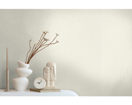 Dekorativ scen med en vas, grenar, ett ljus, en klocka och en skulptur på ett bord.