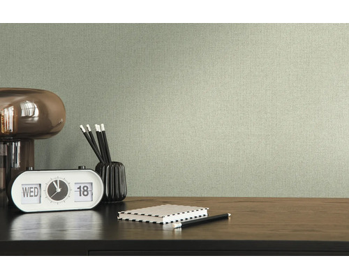 Textiltapet i vardagsrum med skrivbord, lampa, klocka, pennor och anteckningsbok