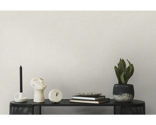 Vardagsrumsdekoration på en hylla med ljus, skulptur, klocka, böcker, skål och krukväxt framför en enfärgad vägg