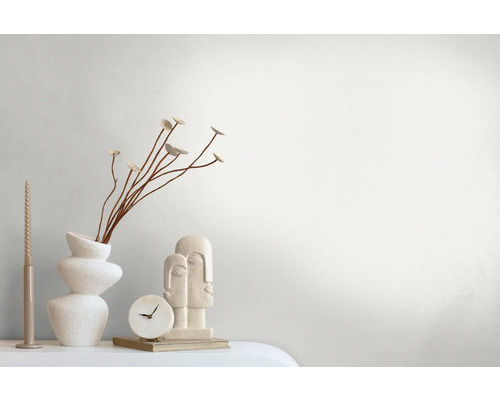 Dekorativt arrangemang med vas, växter, ljus, klocka och skulptur på ett bord