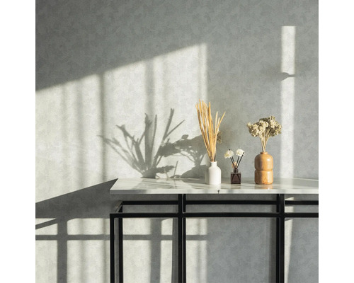 Dekorativa torkade blommor i vaser på ett bord framför en strukturerad vägg.