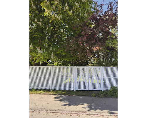 Vitt staket med trädgårdsgrind framför träd
