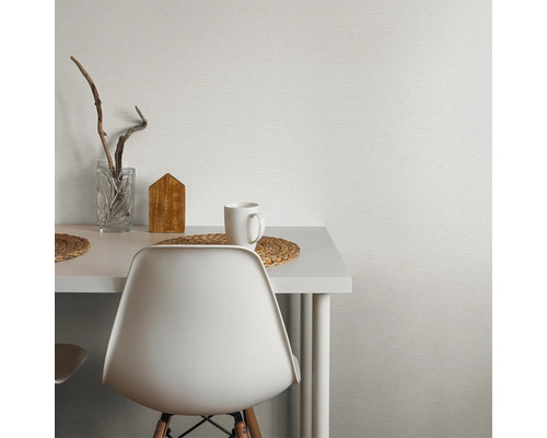 Scen med vitt bord, stol, mugg och dekoration framför en strukturerad tapet