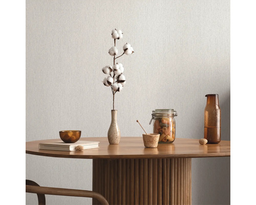 Bordsdekoration med bomullskvist, skål, bok, förvaringsburk och flaska på ett träbord framför en enfärgad vägg.