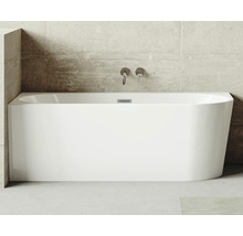 Rektangulärt badkar av sanitetsakryl med armaturer mot en betongvägg