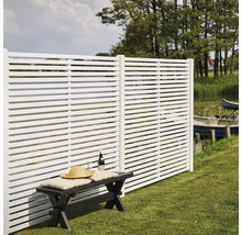 Vita staketselement med horisontella lameller bredvid en sittbänk i trädgården