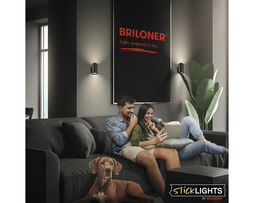 Vardagsrum med soffa, par, hund och två Briloner vägglampor