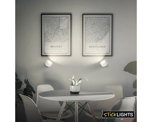 Vardagsrum med matbord, stolar och vägglampor för att belysa inramade stadskartor