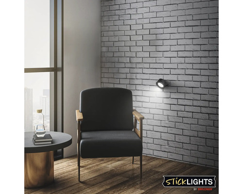 Interiör med fåtölj, sidobord och vägglampa monterad på tegelväggen