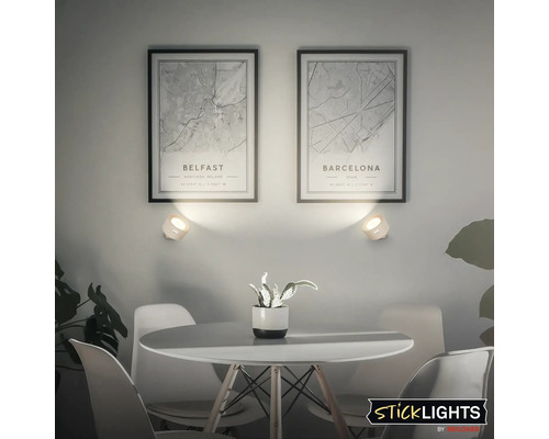 Vardagsrum med runt bord, stolar och två vägglampor ovanför inramade bilder