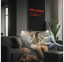 Vardagsrum med par i soffan, upplyst av vägglampor. Briloner-logotyp i bakgrunden.