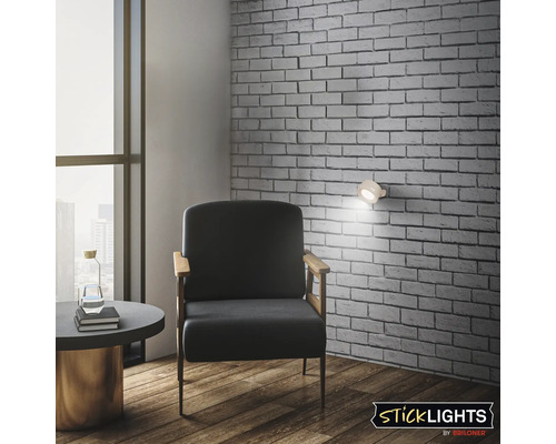 Rum med fåtölj, bord, vägglampa och tegelvägg