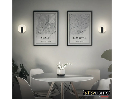 Scen med två vägglampor, två inramade stadskartor över Belfast och Barcelona, ett bord och stolar