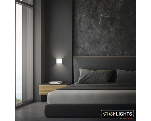 Modernt sovrum med dubbelsäng, nattduksbord och fyrkantig vägglampa