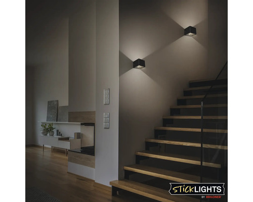 Vardagsrum med trappa och två fyrkantiga vägglampor