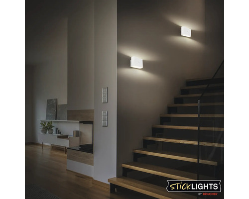 Två fyrkantiga vägglampor i plast lyser upp en trappa.