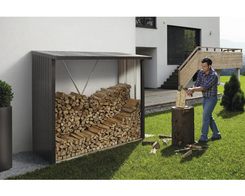 Vedförråd med ved och man som hugger ved i trädgården.