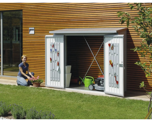 Trädgårdsskåp med öppna dörrar, utrustat med trädgårdsredskap, gräsklippare och vattenkanna i trädgården.