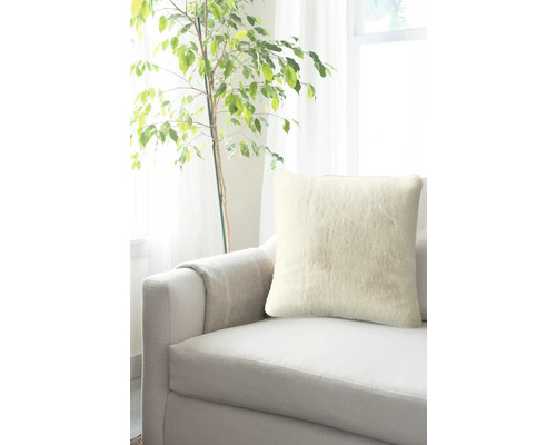 Prydnadskudde på en soffa bredvid en krukväxt