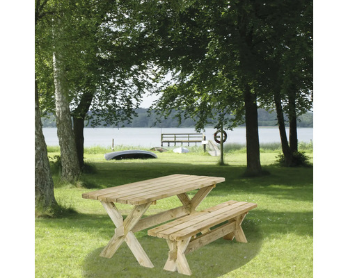 Trädgårdsträbord med bänk på en gräsmatta vid sjön