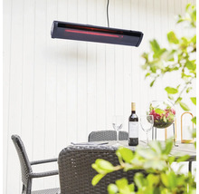 Uteplats med värmelampa, bord, stolar, vin och dekoration för en mysig atmosfär