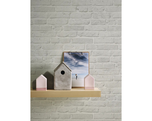 Vägg med tegel tapet, trähylla med husdekorationer och bild på ett clipbräde