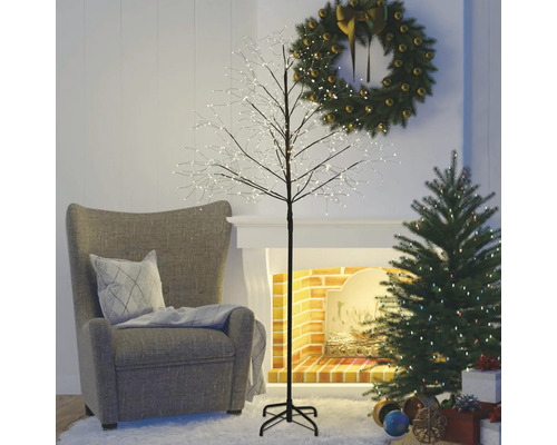 Vardagsrum med fåtölj, julgran, adventskrans och upplyst dekorativt träd