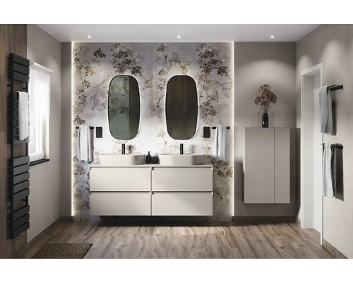 Ljust badrum med dubbla handfat, underskåp, speglar och blommig tapet.