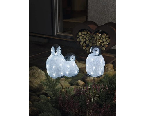 Tre lysande pingvinfigurer som dekoration i trädgården.