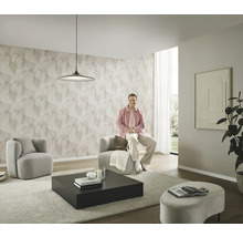 Modernt vardagsrum med mönstrad tapet, två fåtöljer, ett soffbord och en person