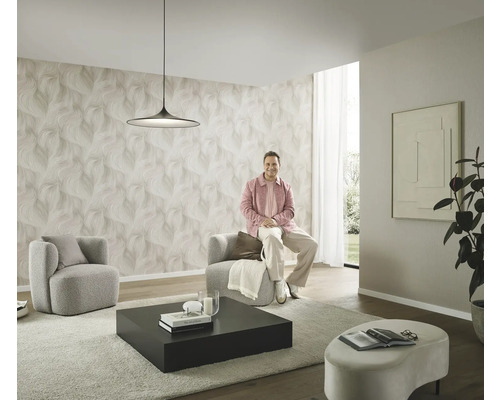 Modernt vardagsrum med mönstrad tapet, två fåtöljer, ett soffbord och en person