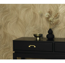 Dekorativ tapet med vågigt mönster bakom ett svart bord med en guldskål och vas