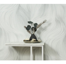 Miljöbild med en vit tapet med vågigt mönster och bordsdekoration med en vas