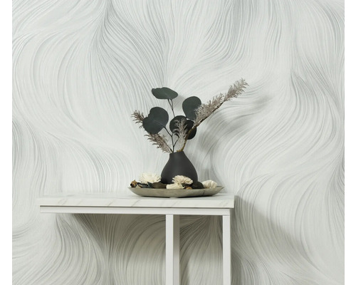 Miljöbild med en vit tapet med vågigt mönster och bordsdekoration med en vas