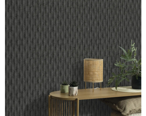 Närbild av en vägg med en strukturerad tapet, ett bord med en lampa och växter